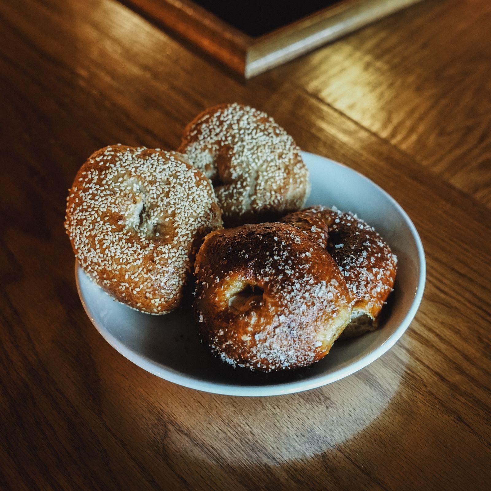 A bowl of assorted fresh bagels on a wooden table