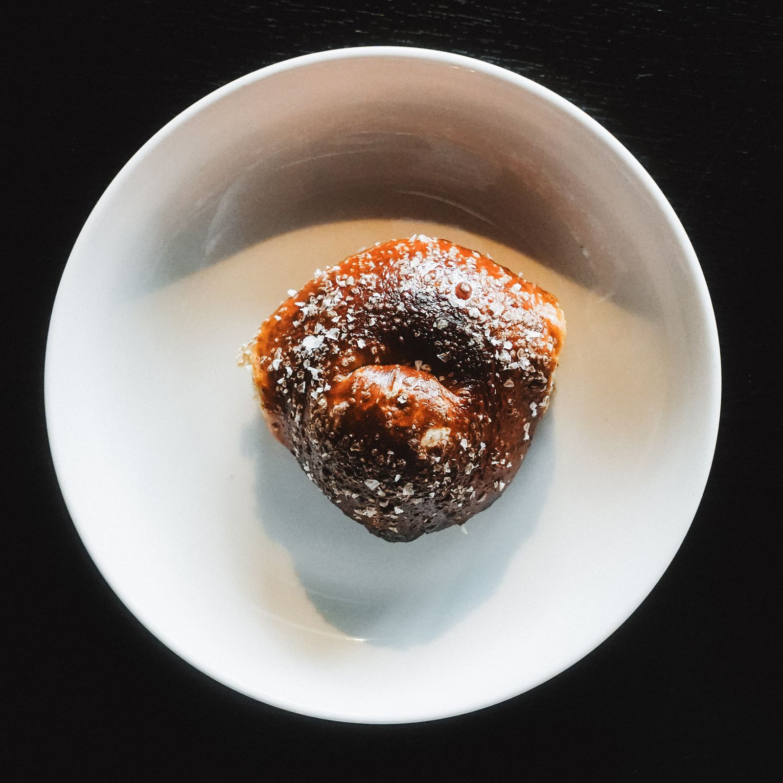 A chocolate bagel dusted with powdered sugar
