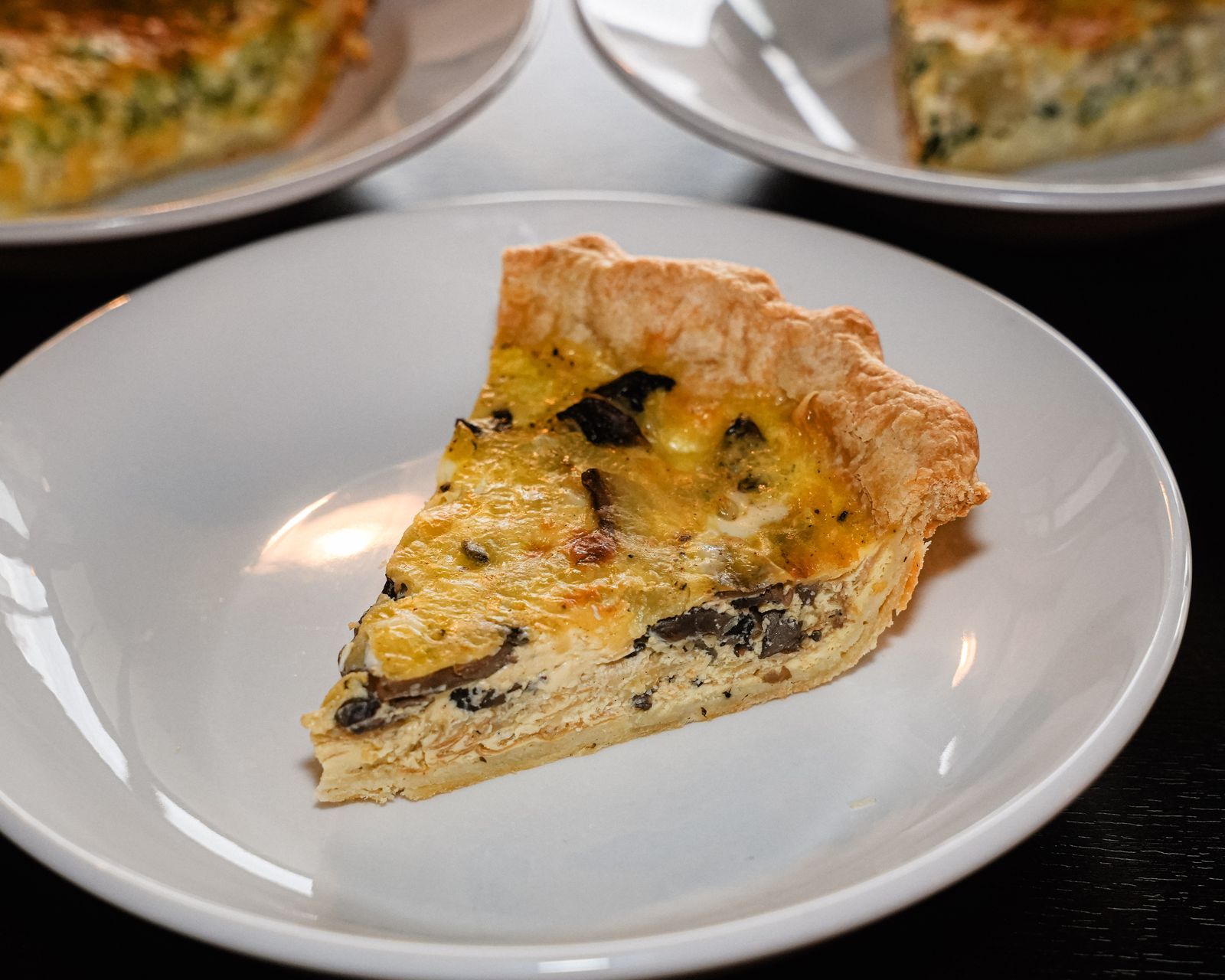 A slice of quiche on a white plate